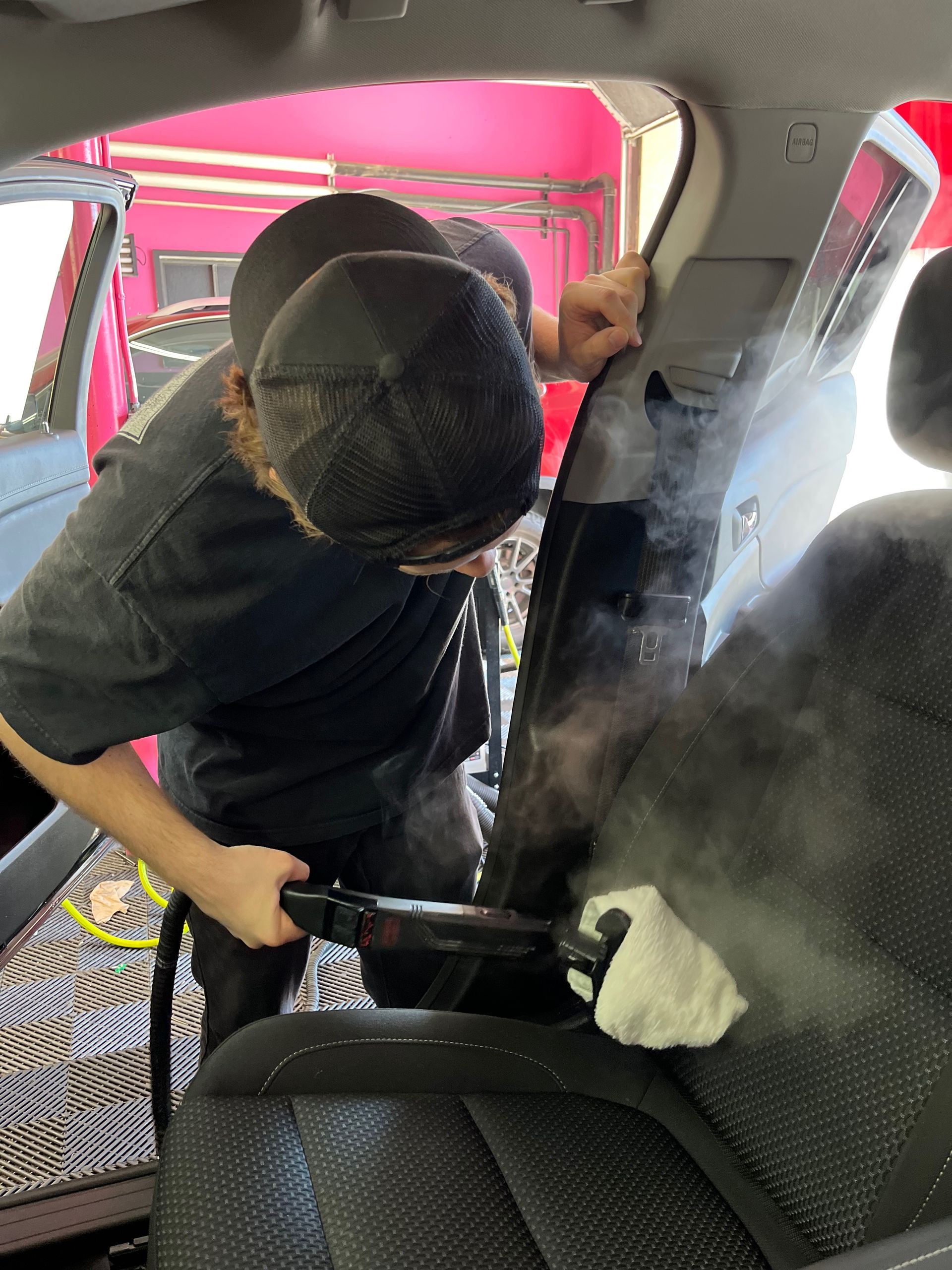 Steam cleaning a seat using our signature European Steam Treatment process at Stokes Auto Spa.