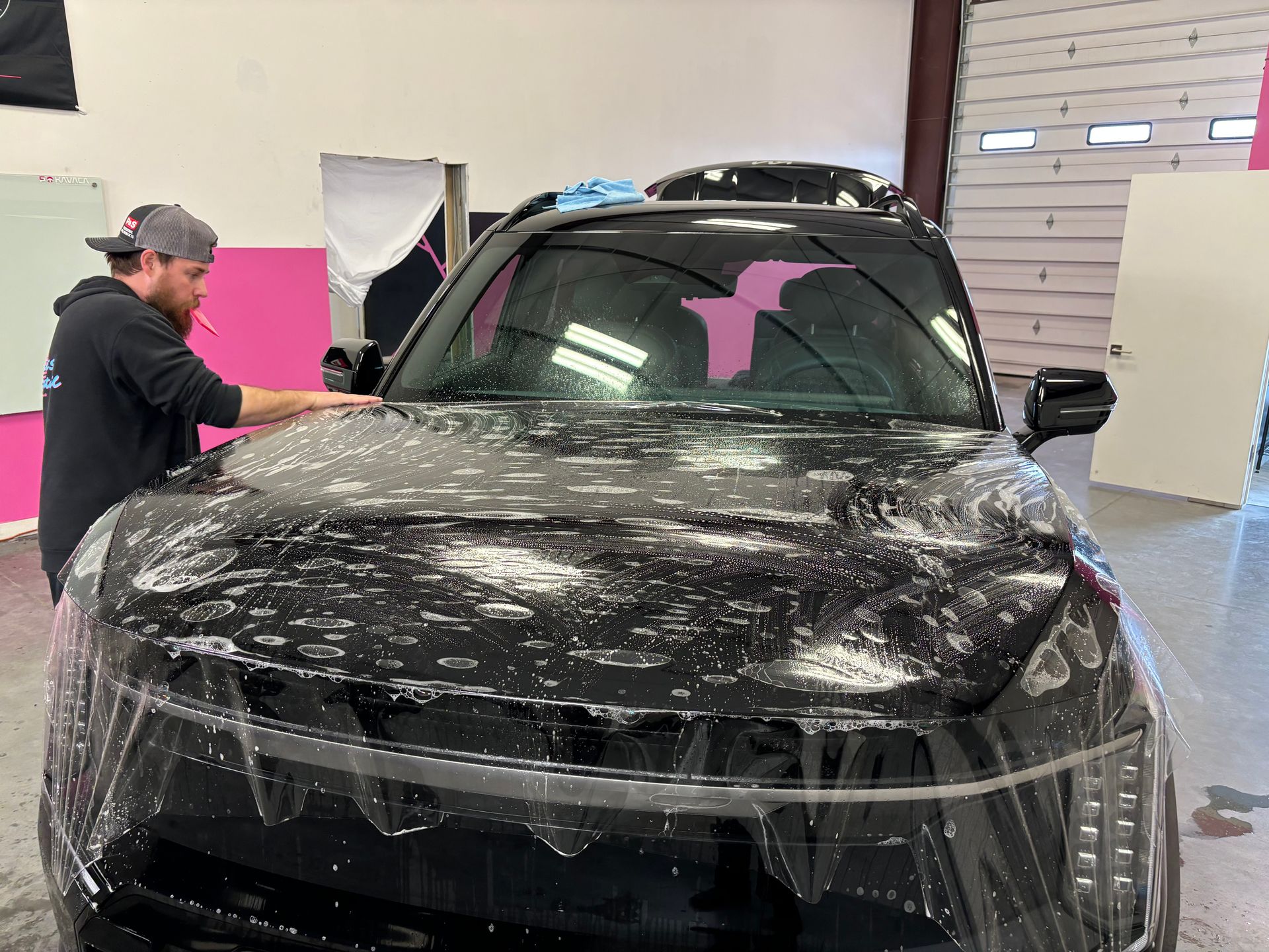 Paint Protection Film Installation on a Kia EV9. Britt Stokes is installing paint protection film to the entire hood as part of the Full Front PPF package at Stokes Auto Spa.