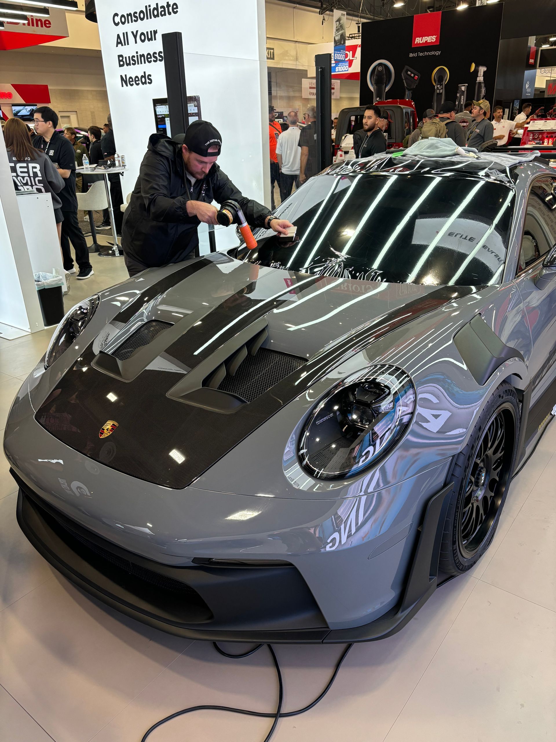 A man is tinting the windshield of a gray Porsche