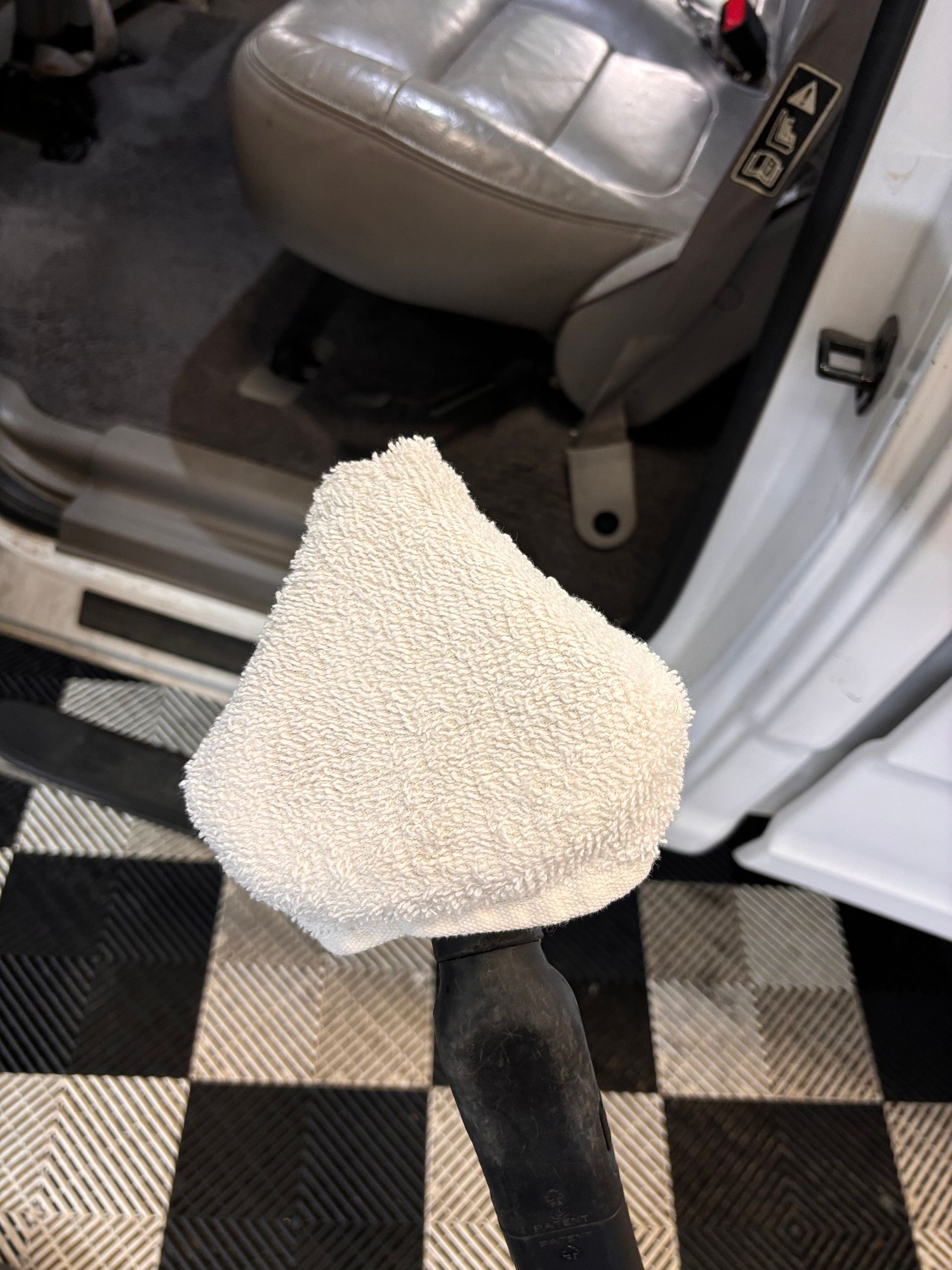 White steam cleaner head cleaning a car interior.