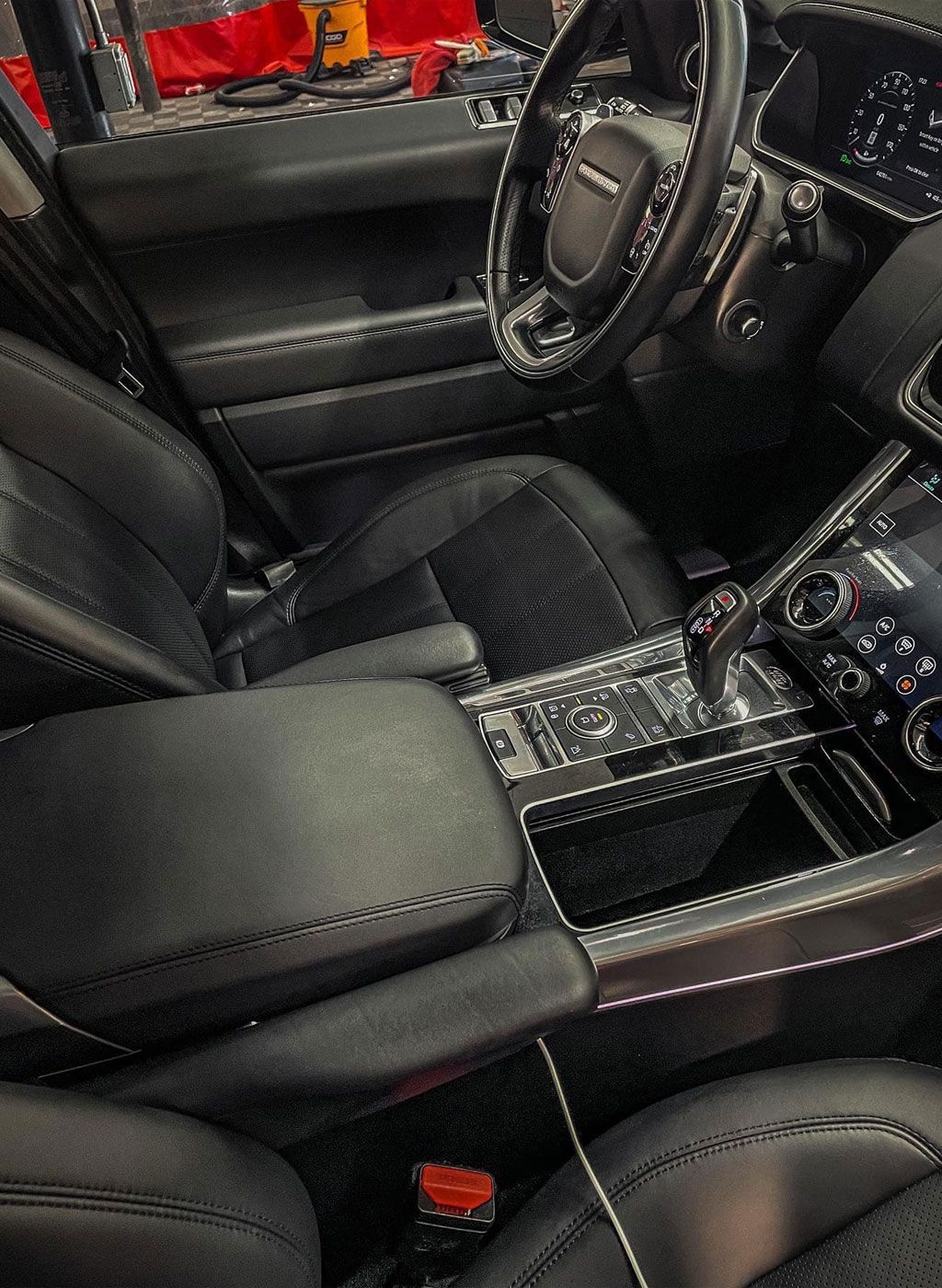 Black leather interior of a Range Rover, showing the driver's seat, steering wheel, and console.