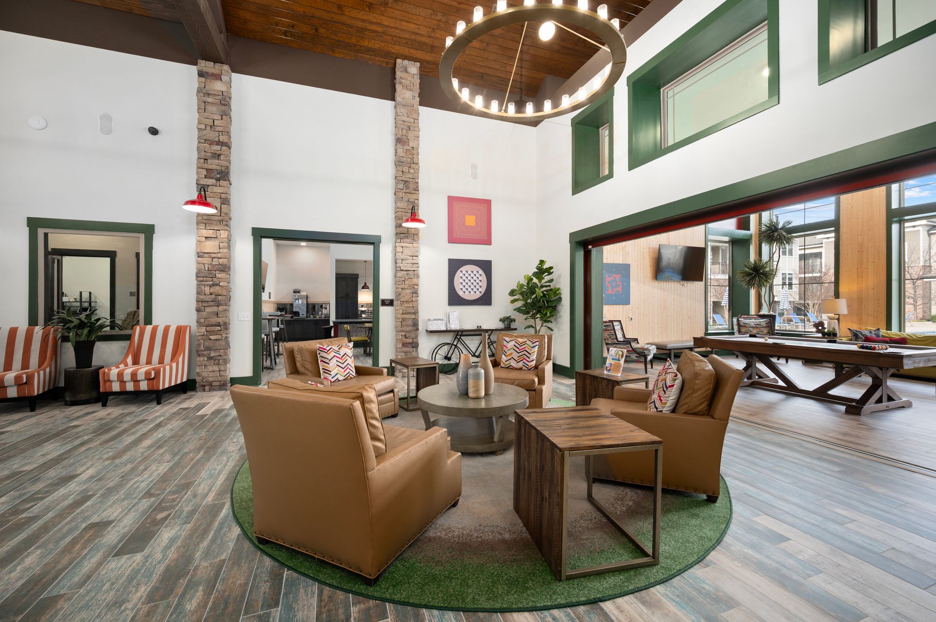 A bright community lounge with a large circular chandelier, leather chairs, and a pool table in an open, airy space at Silver Collection at Cosner's Corner in Fredericksburg, VA.