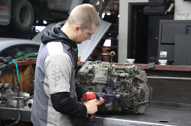 A man is working on a car engine in a garage