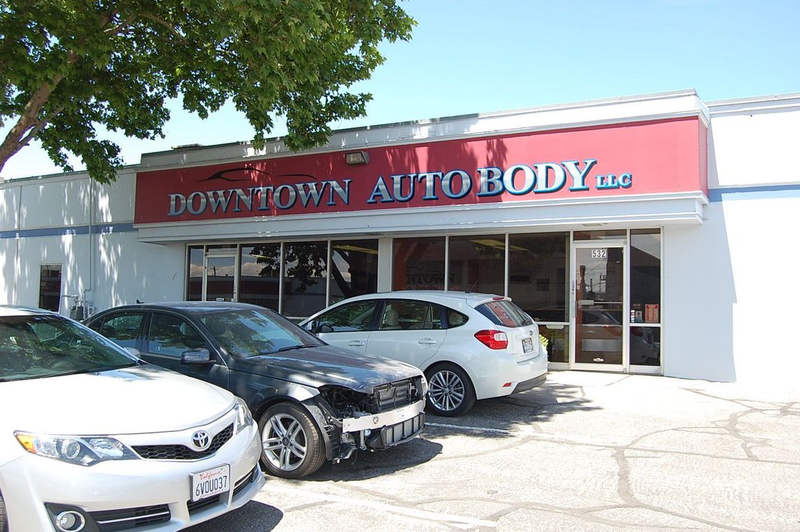 Downtown Auto Body storefront with parked cars in front under a red awning