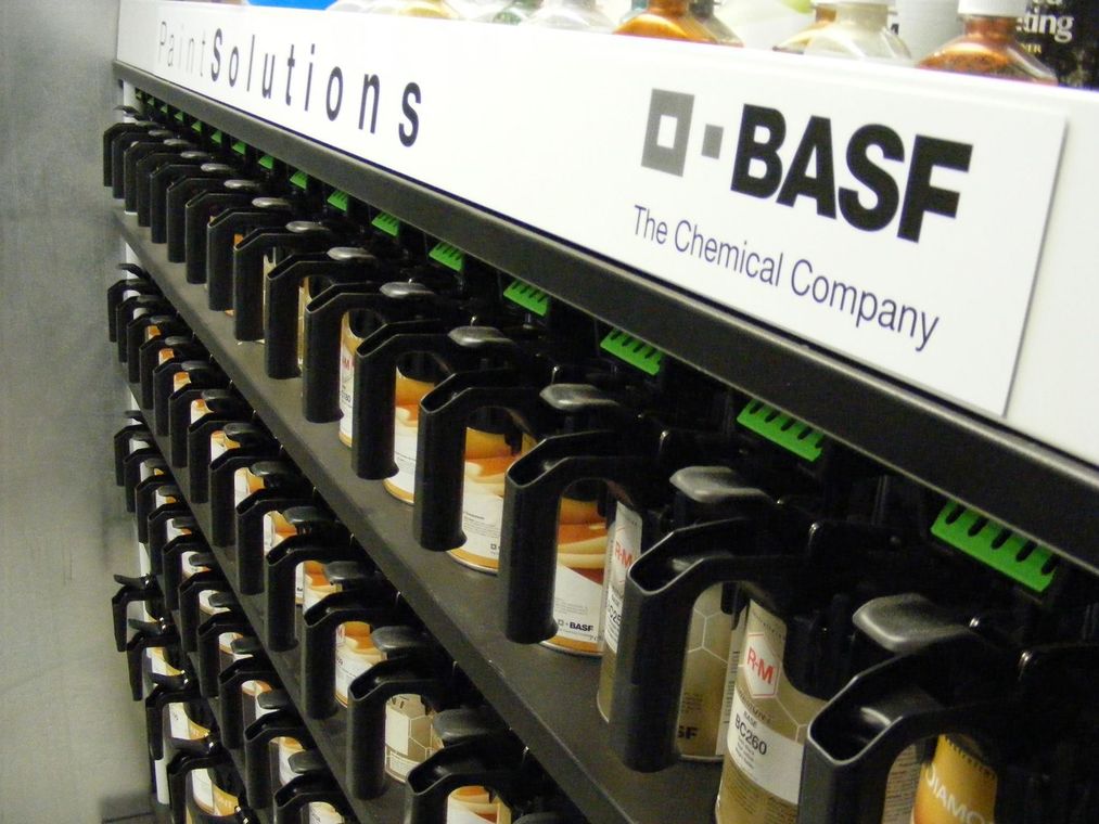Rows of chemical containers on shelves beneath a BASF sign in a laboratory or storage area