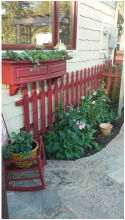 A rocking chair is sitting in front of a red picket fence.