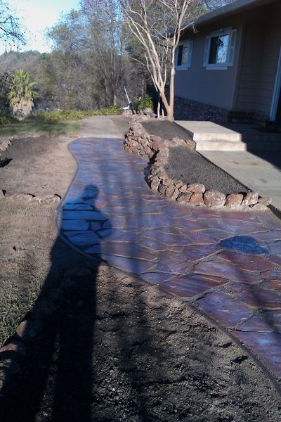 A person is standing on a sidewalk in front of a house.