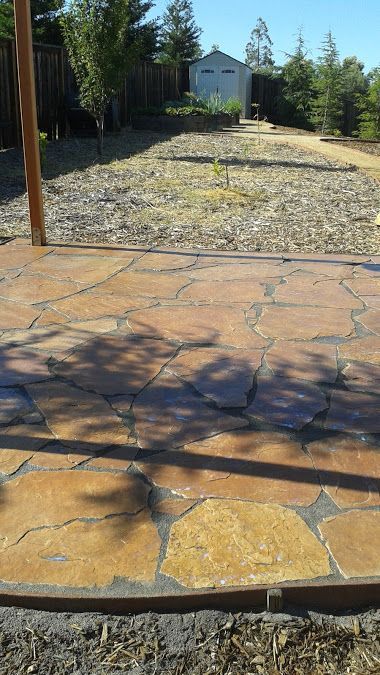 A stone patio in a backyard with a house in the background.