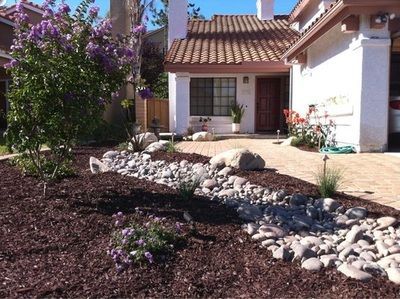 A house with purple flowers and rocks in front of it