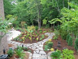 A stone walkway leading to a pool in a backyard surrounded by trees.