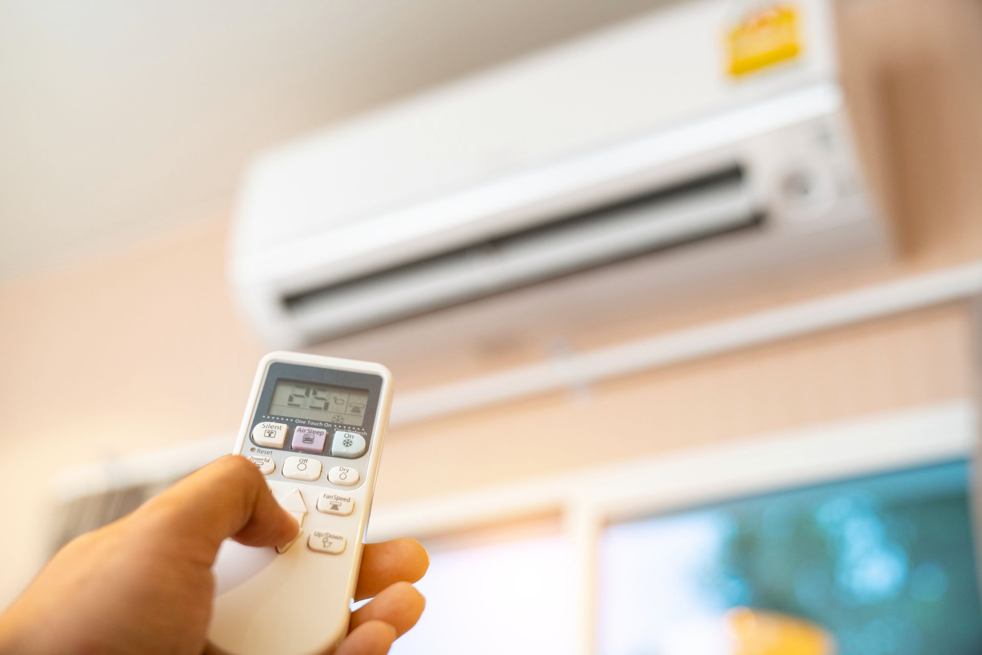 A white air conditioner is mounted on a wall next to a television mount.