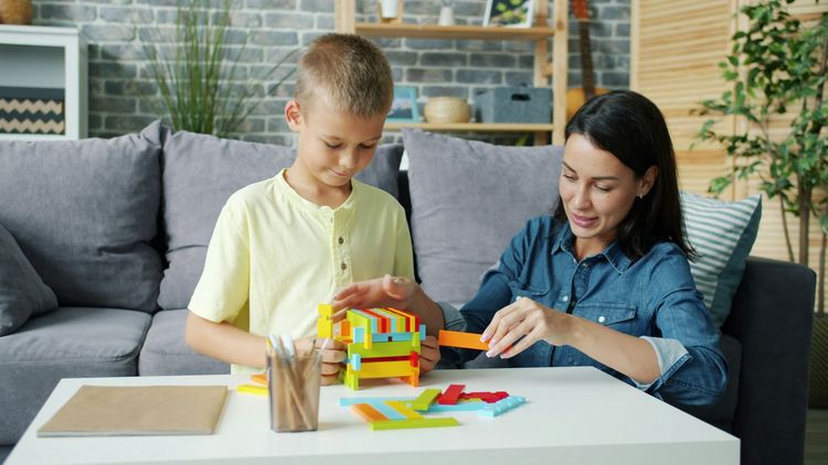 Two children building a colorful toy on a table in a cozy living room