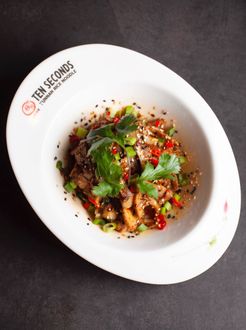 Overhead view of a garnished dish on a white plate against a dark background