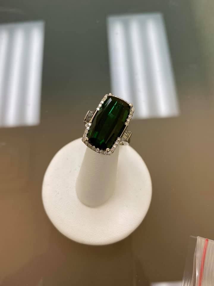 Dark green gemstone ring on a white display stand