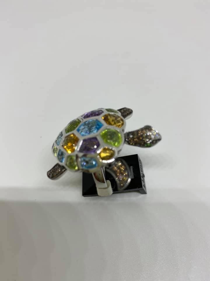 Colorful jeweled turtle figurine on a small black stand against a plain white background
