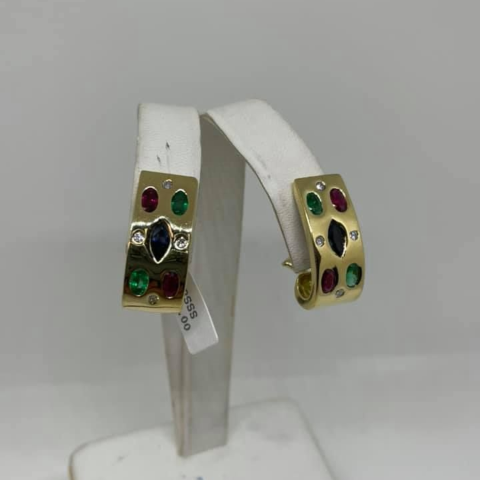 White display stand holding gold jeweled hoop earrings with red and green stones