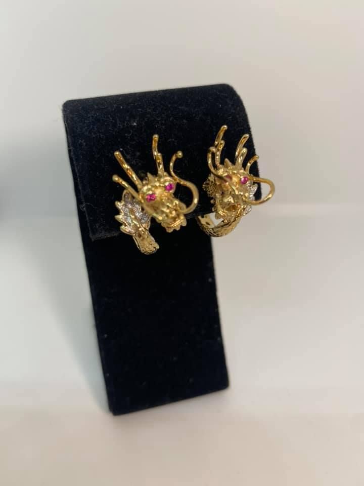 Gold dragon-shaped earrings displayed on a black velvet stand.