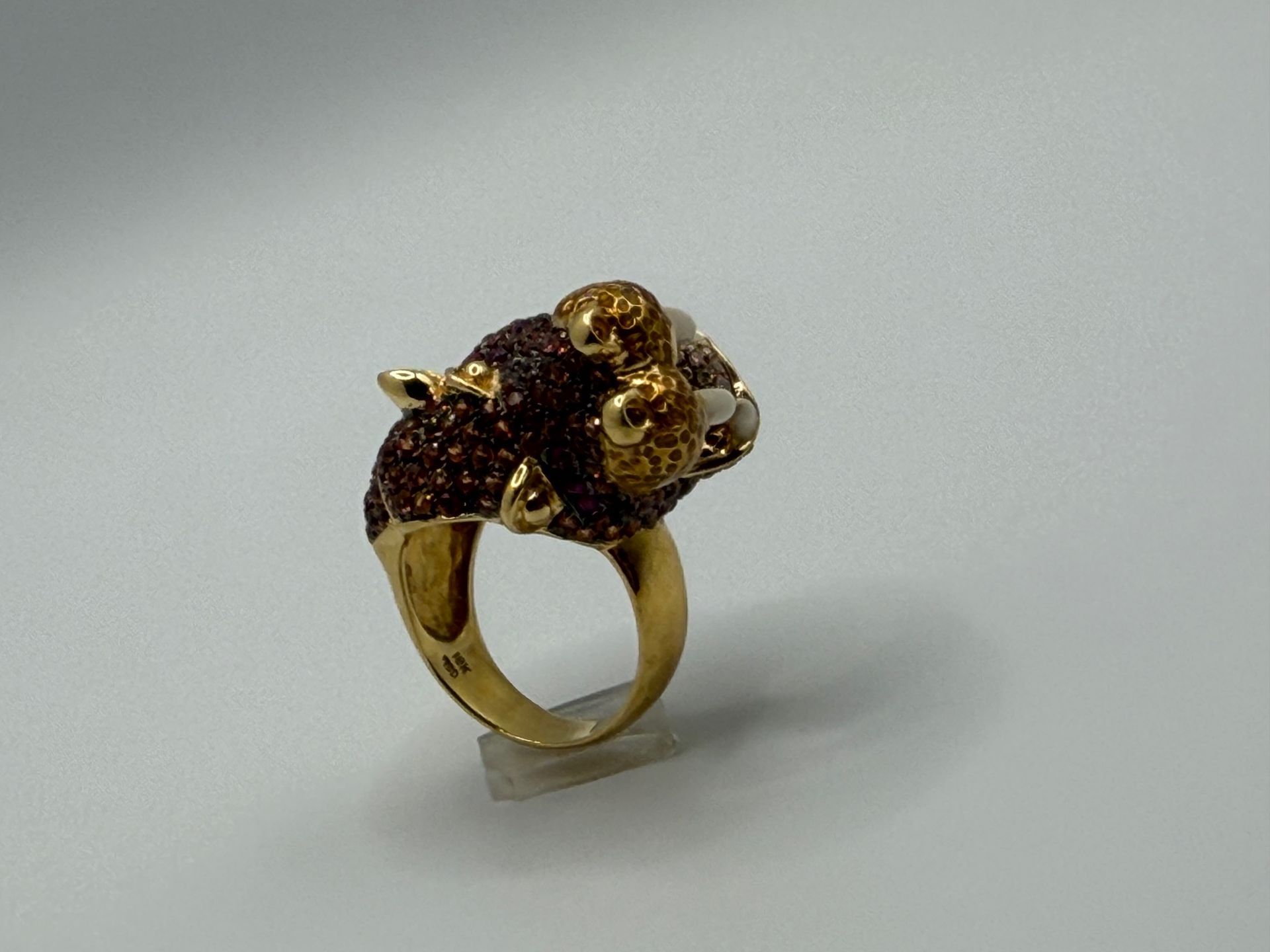Gold ring with a brown gemstone and small decorative accents on a light gray background