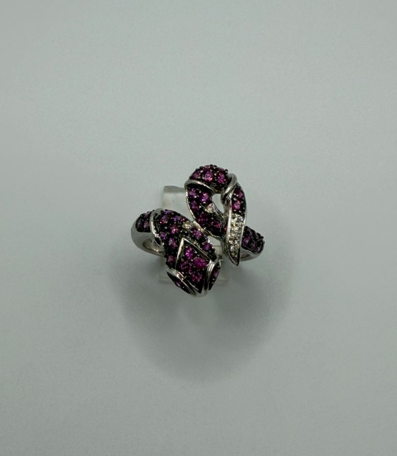 Pair of silver knot earrings with dark pink stones on a light gray background