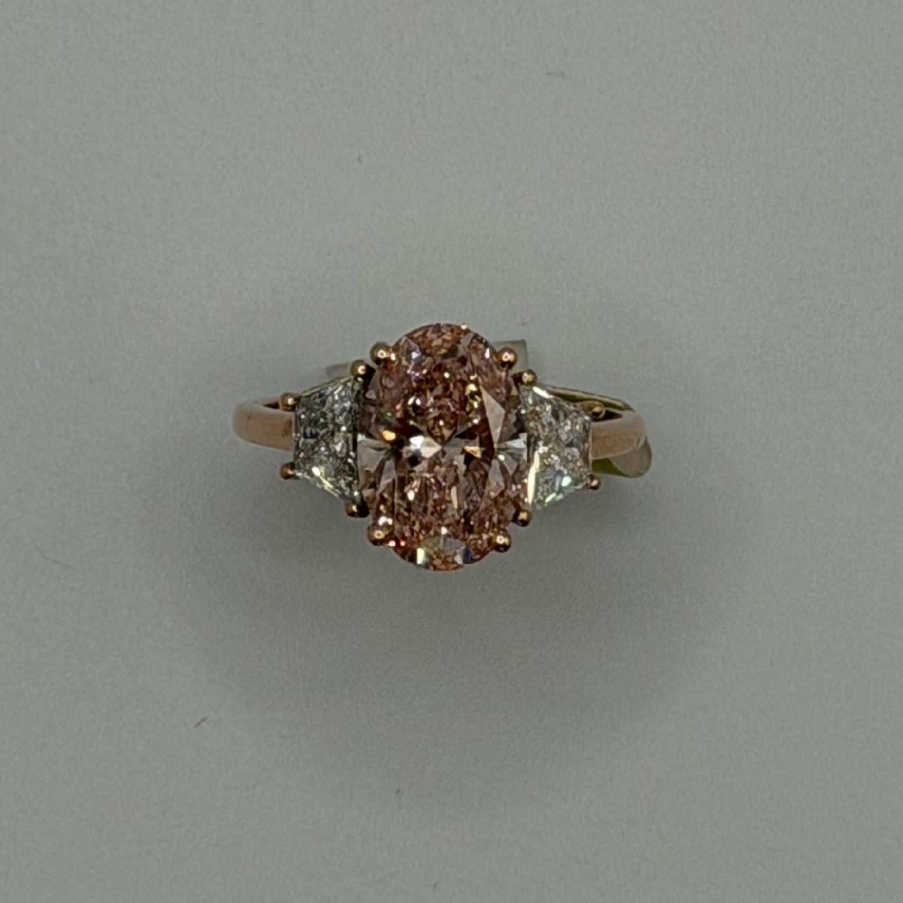Oval pink and white diamond ring on a plain gray background