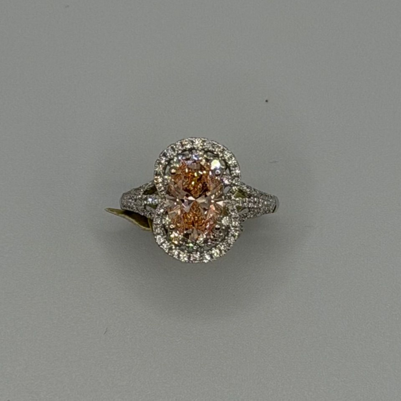Silver ring with two oval orange gemstones surrounded by small clear stones on a gray background