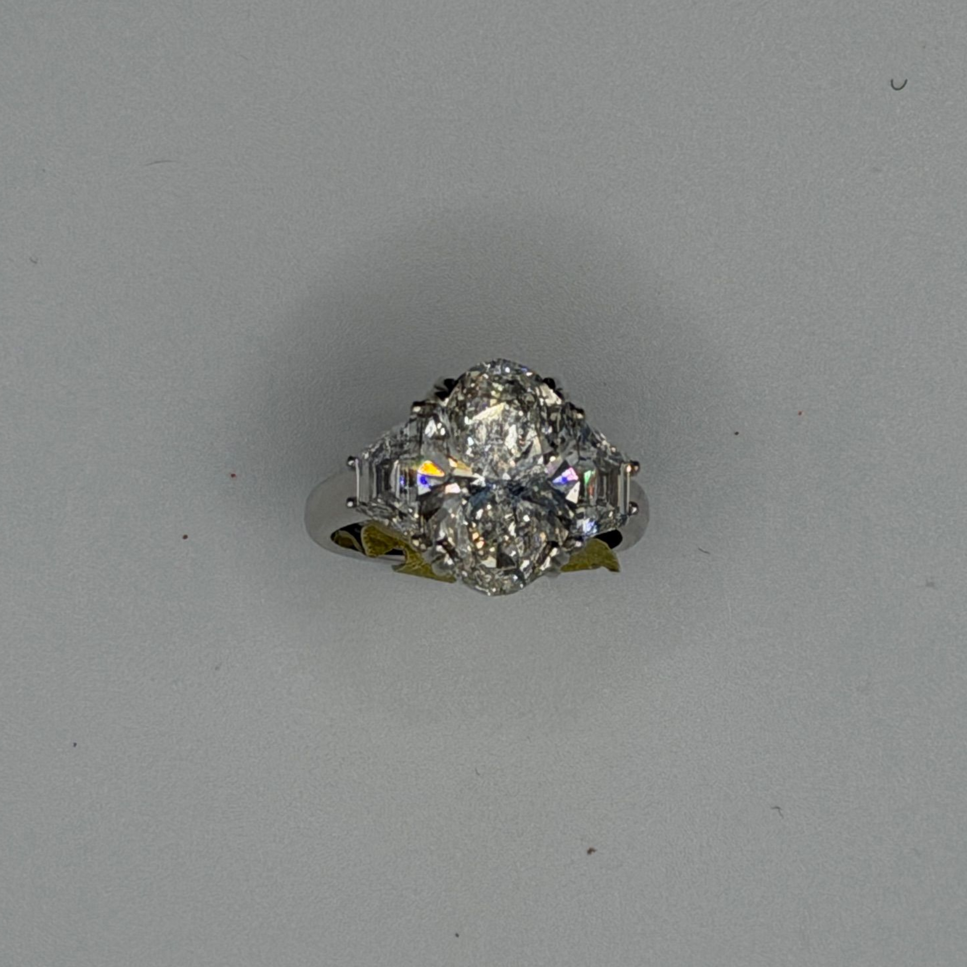 Diamond ring with a large sparkling center stone on a plain gray background
