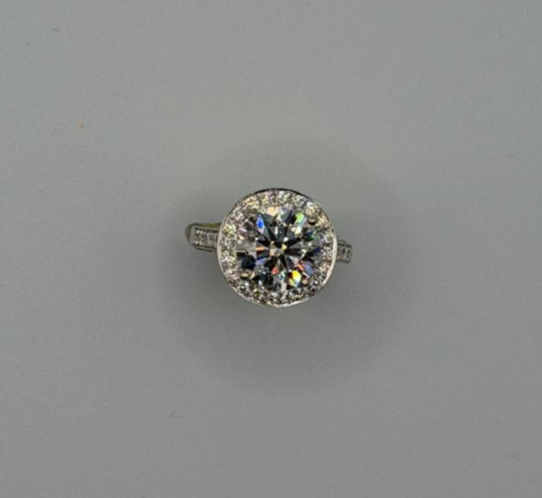 Silver ring with a large round clear gemstone and small side stones on a gray background