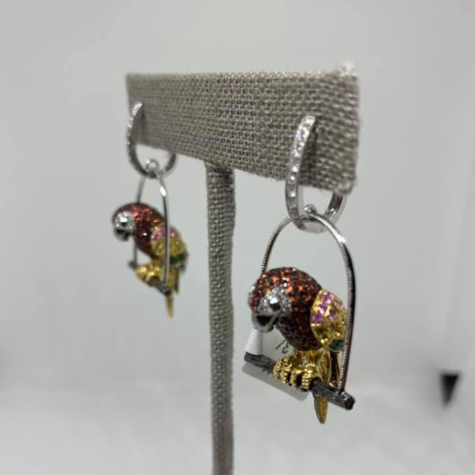 Sparkly bird-shaped silver hoop earrings on a gray display stand