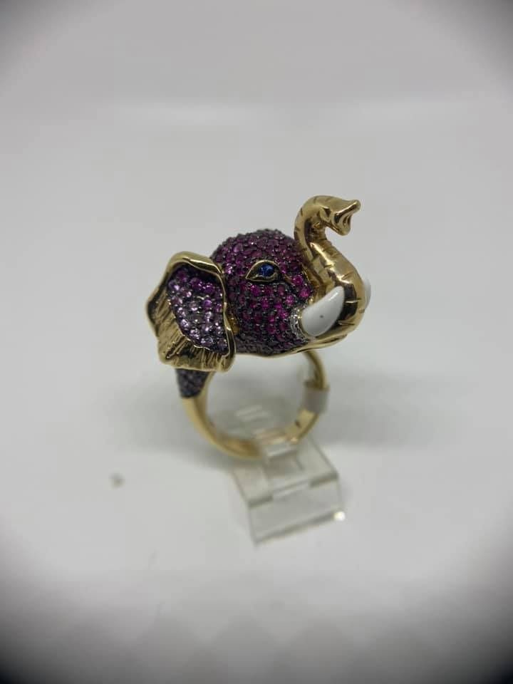 Gold and silver ring with a green gemstone centerpiece on a light gray background