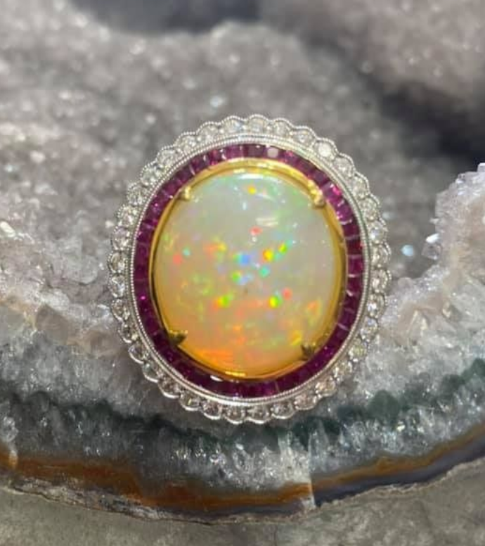 Opal ring with a gold halo and purple accent set on gray crystal rock