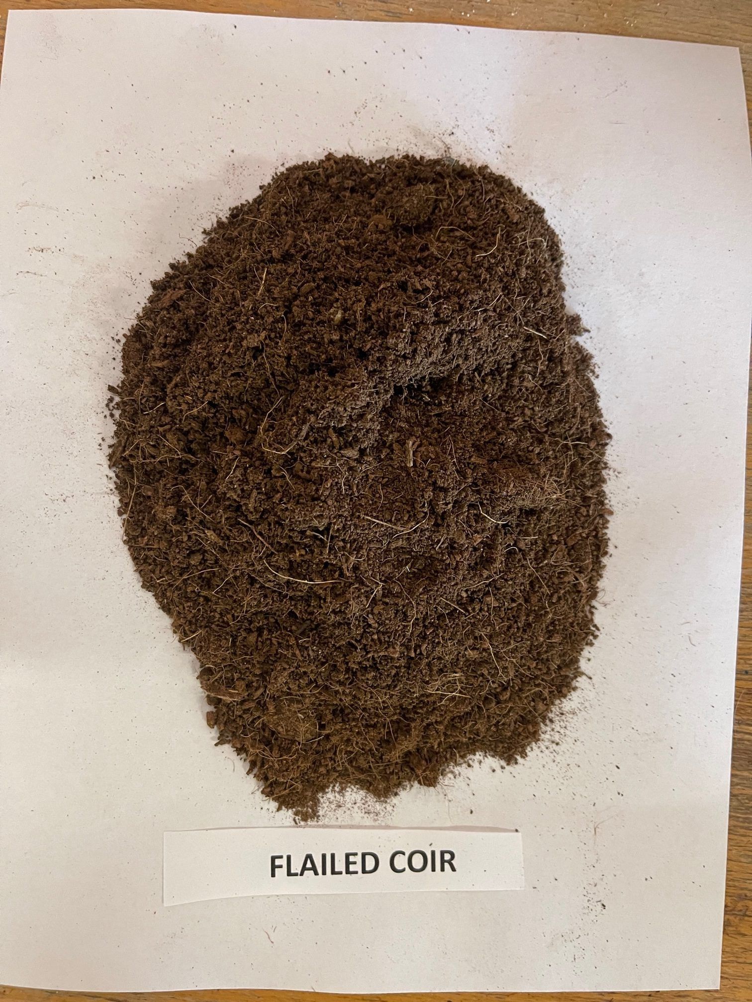 Brown pile of flailed coir on white paper, labeled 