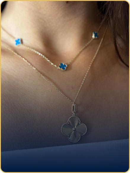 A woman is wearing a necklace with a four leaf clover pendant.