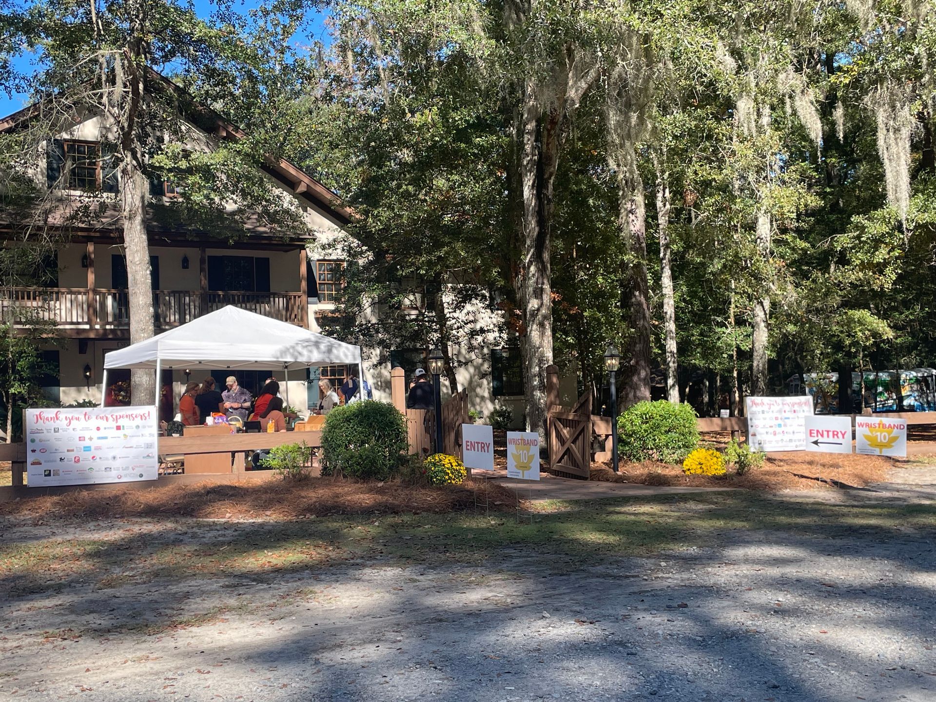 White tent set up outdoors, with colorful signs and a building in the background.