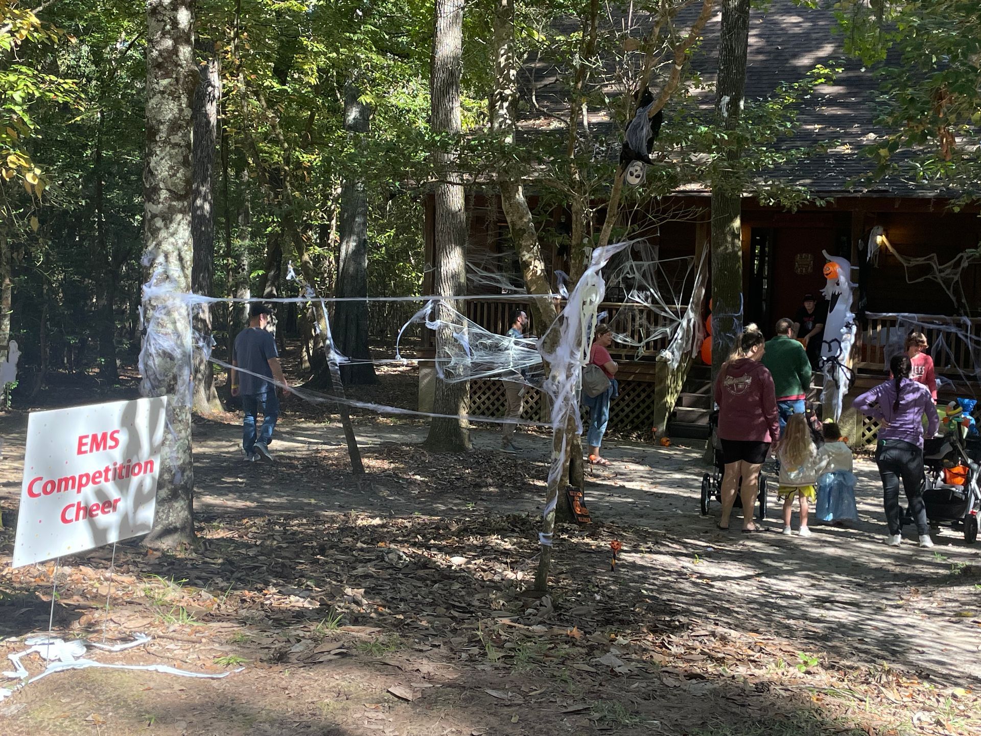 People line up at a Halloween event outside a building decorated with cobwebs and lights.