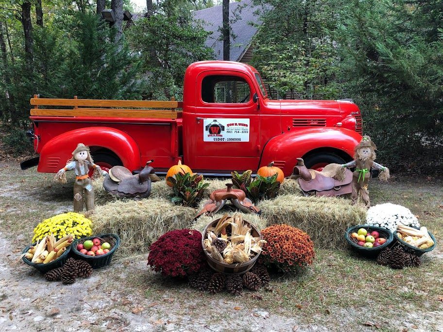 Red vintage truck decorated for fall with pumpkins, mums, and scarecrows.