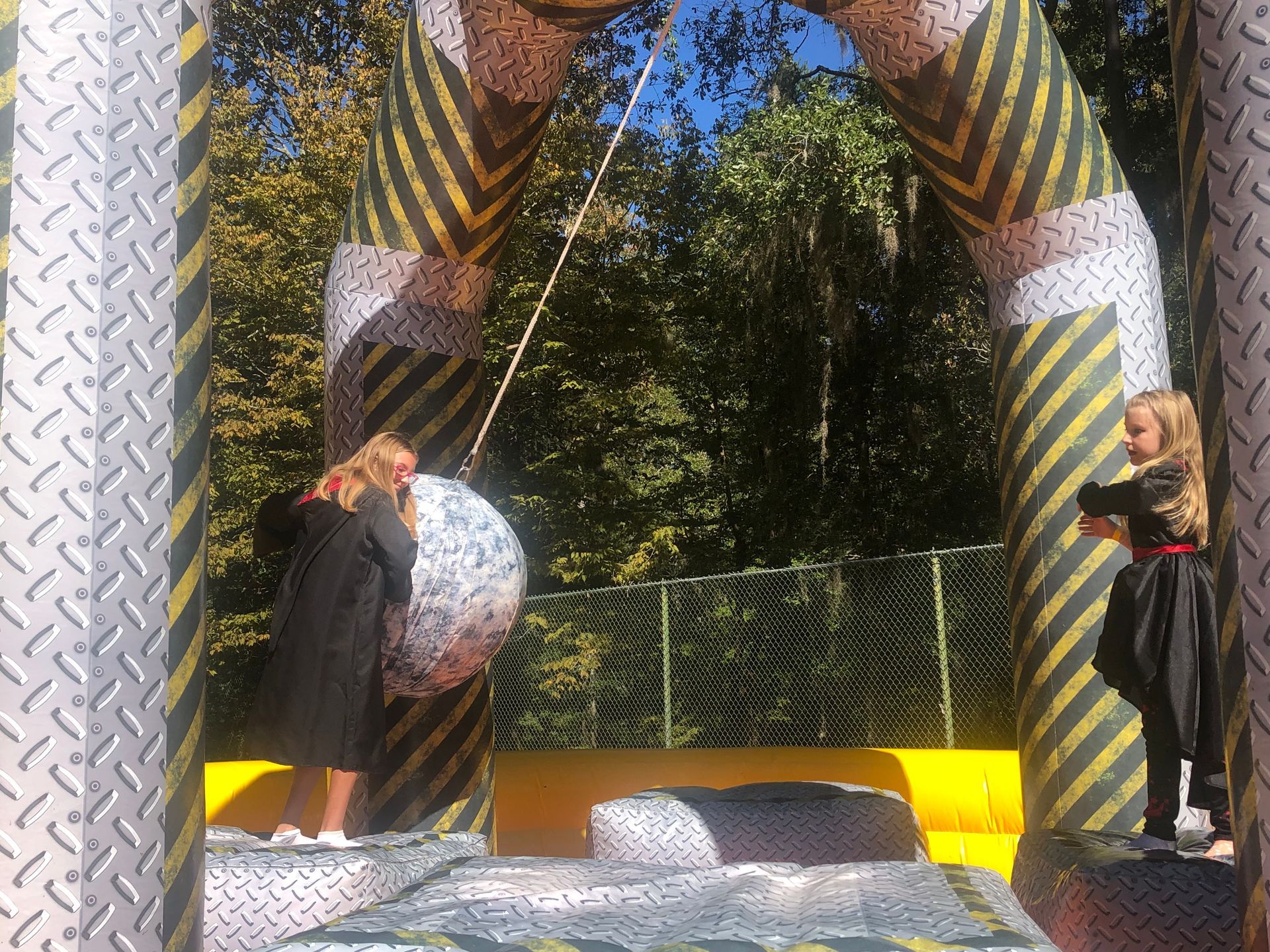 Two girls playing a wrecking ball game inside a large inflatable structure.