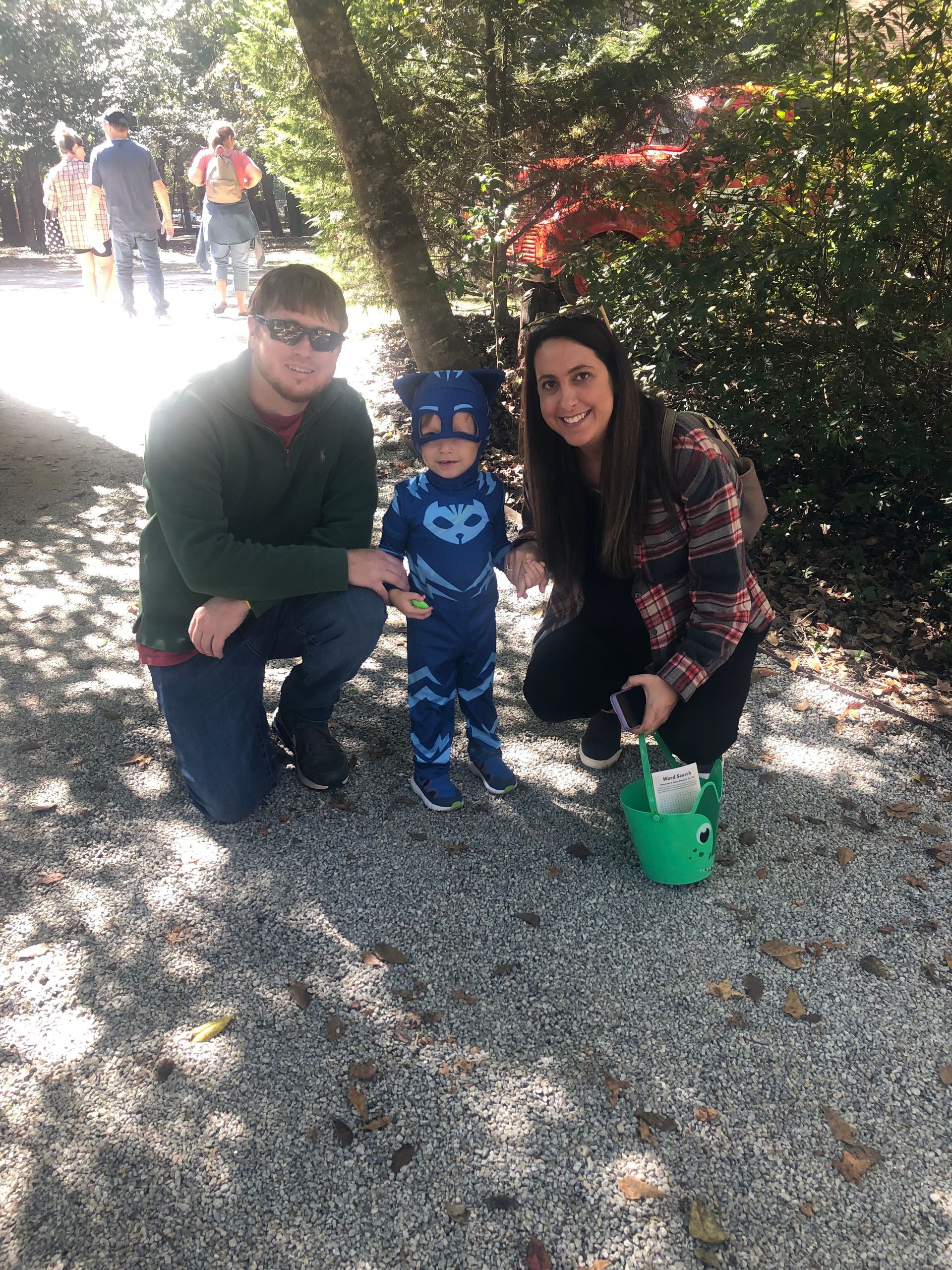 Family, including a child in a Catboy costume, poses outdoors on a gravel path.
