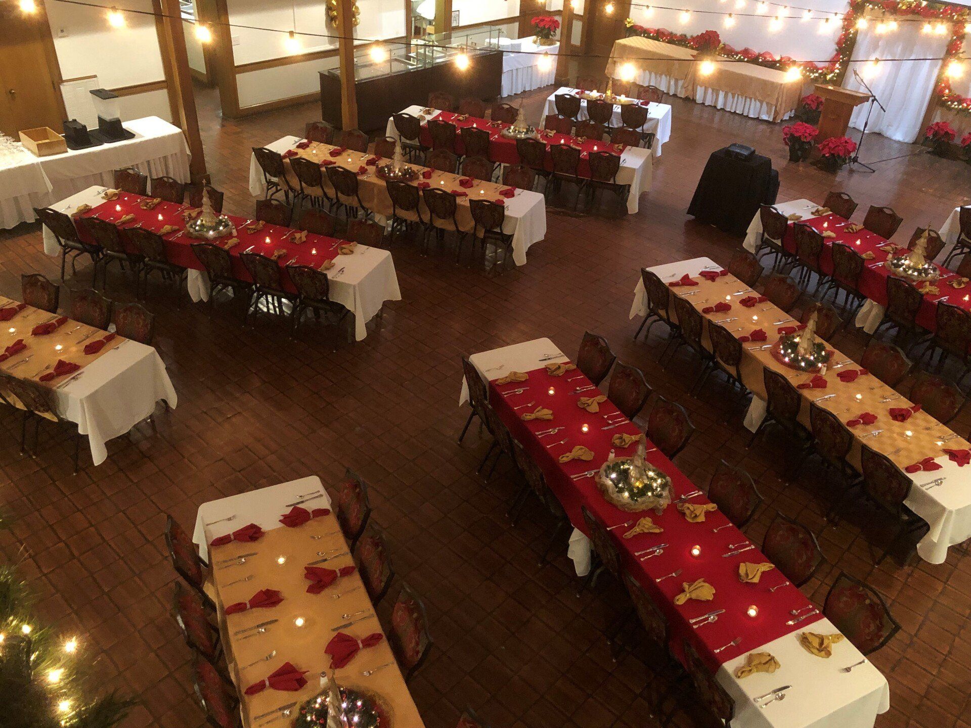 An overhead view of a banquet hall set up with long tables covered in white and red tablecloths.