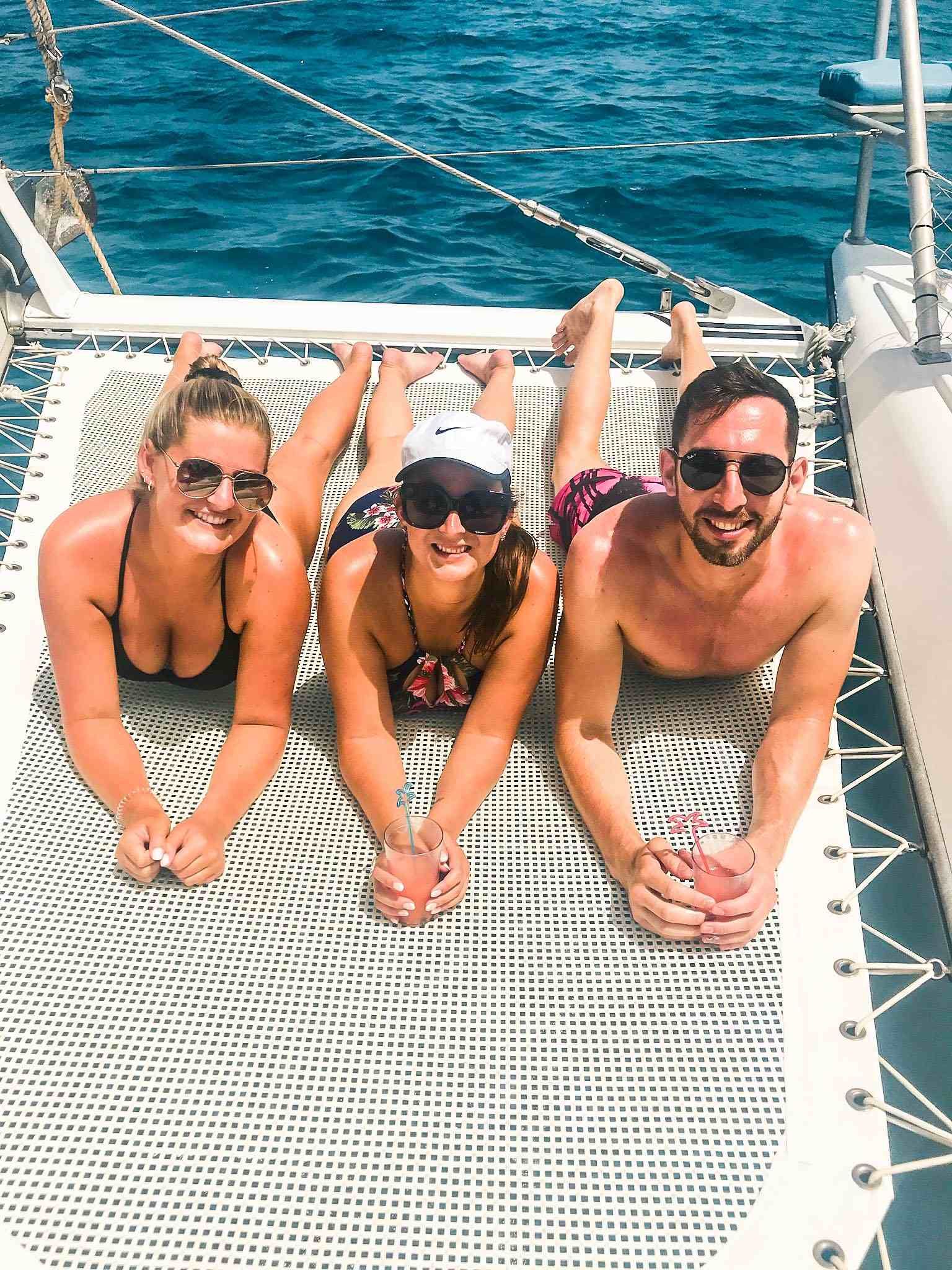 Group of young adults sitting in yacht catamaran charter