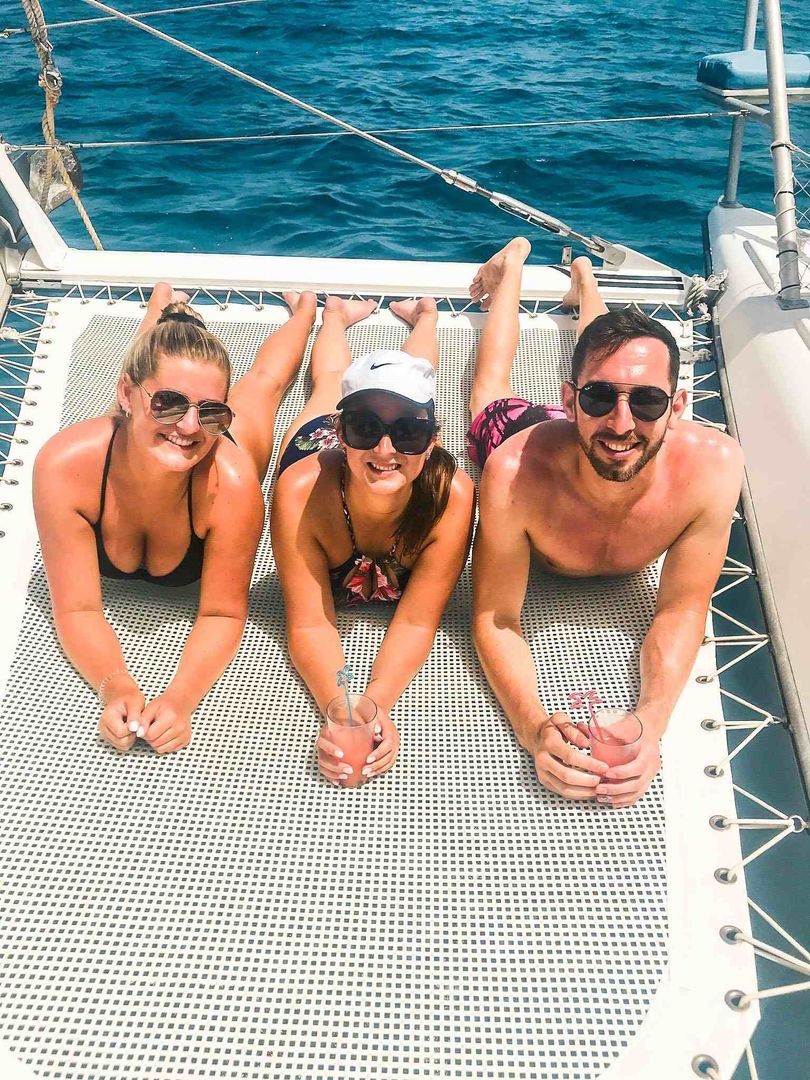 Group of young adults sitting in yacht catamaran charter