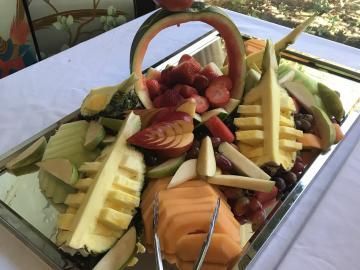 Fruit and vegetable platter arranged in a basket with melon, strawberries, and sliced apples