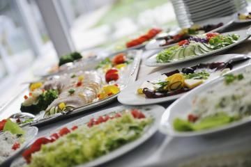 Buffet table with assorted salads, vegetables, and plated dishes at a catered event