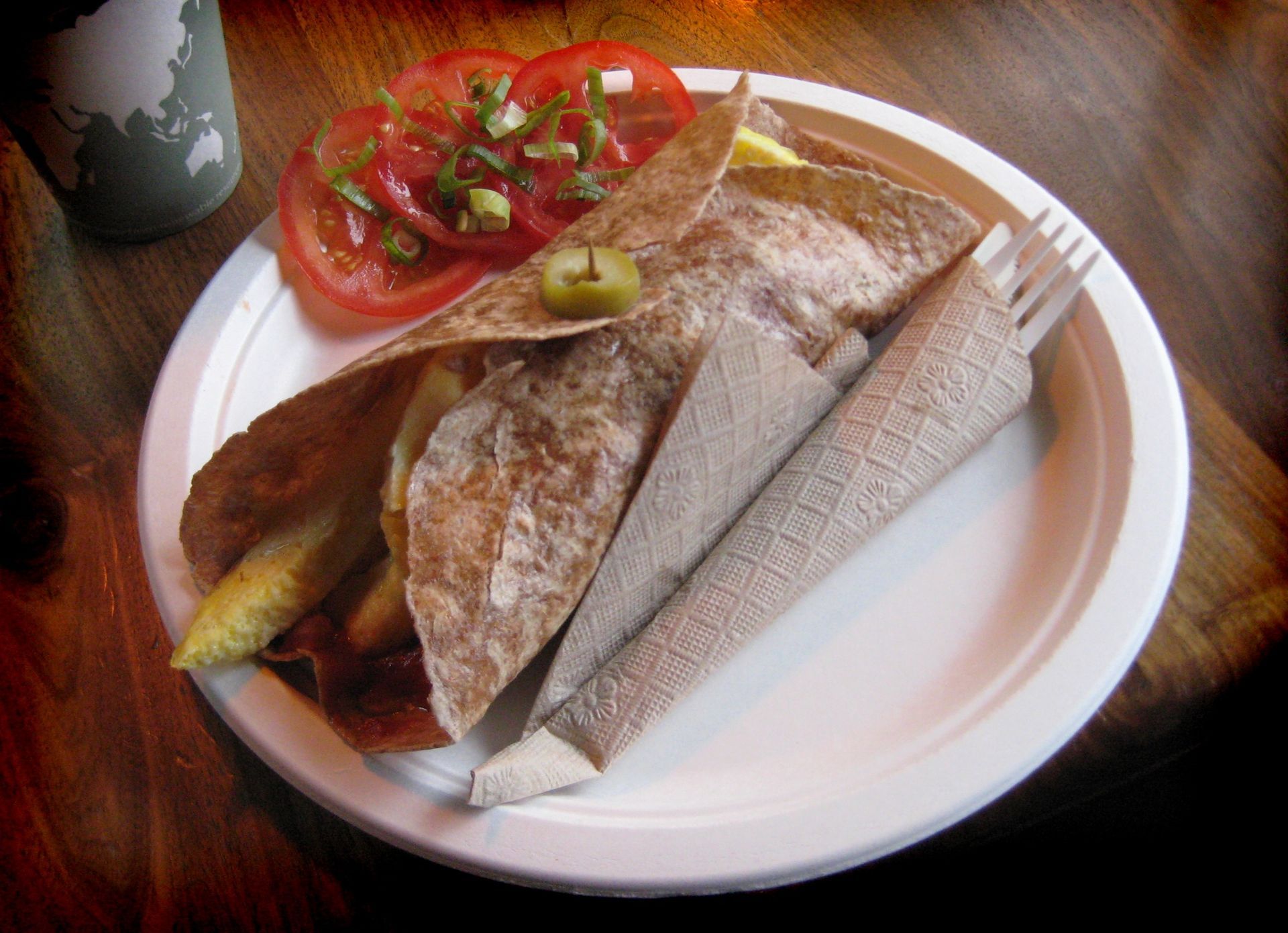 Plate with fish, tomato slices, and lemon wedges on a wooden table