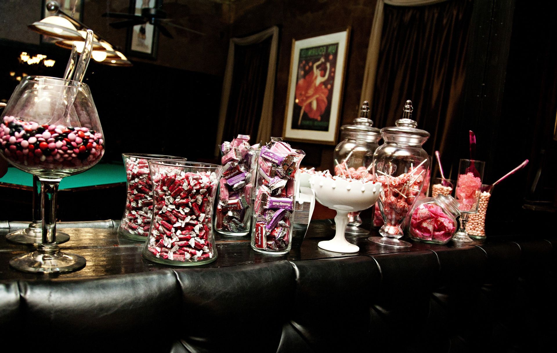 Candy buffet with pink and silver jars and jars of sweets on a black table