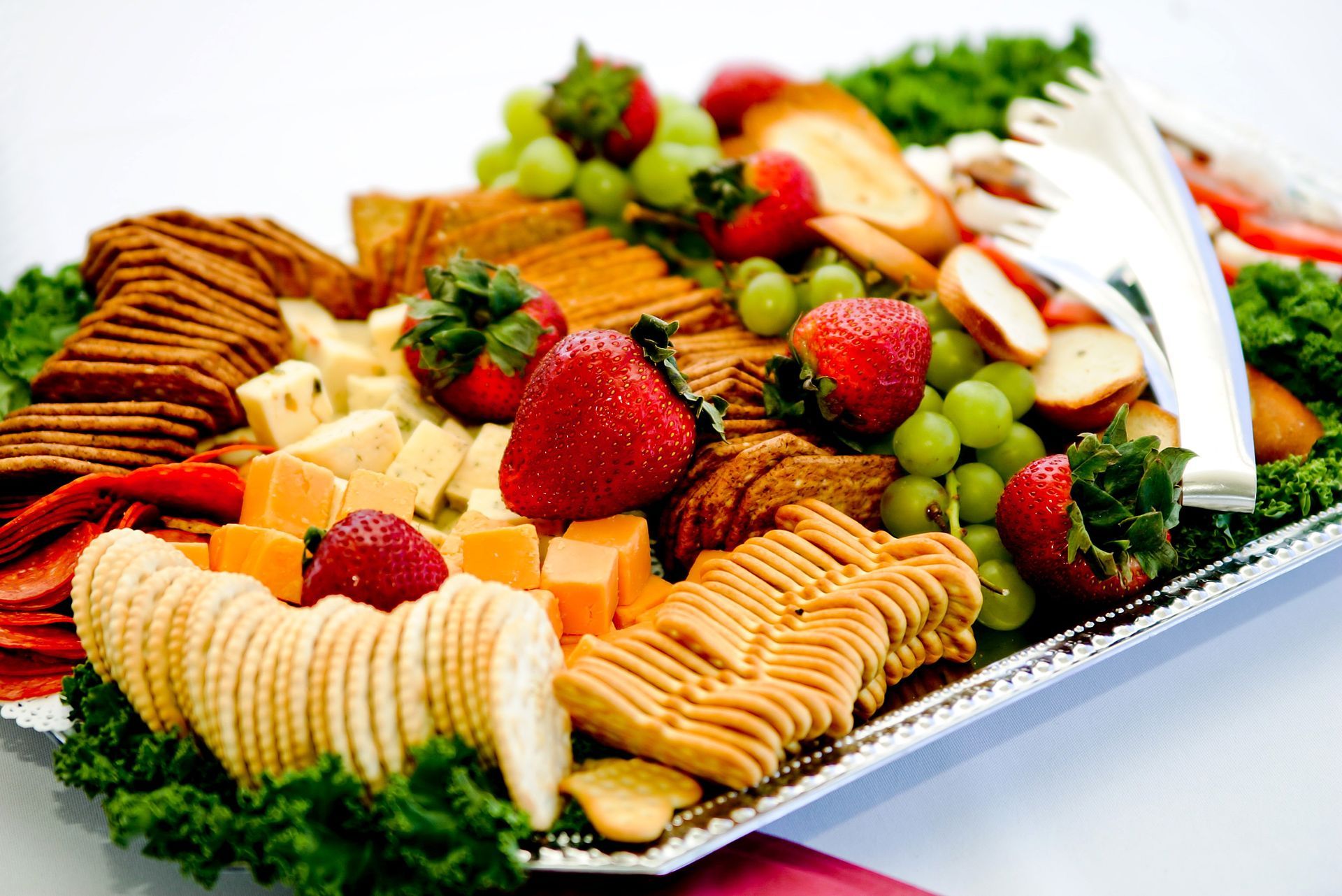 Assorted crackers, cheese, strawberries, and grapes arranged on a serving tray