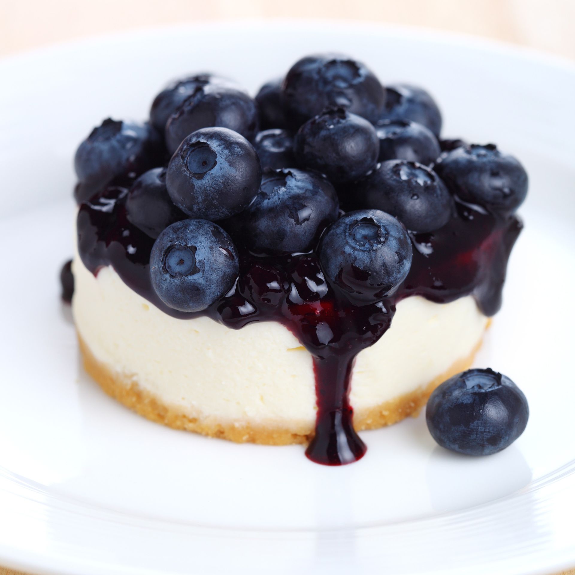 Blueberry-topped cheesecake with dark berry sauce on a white plate