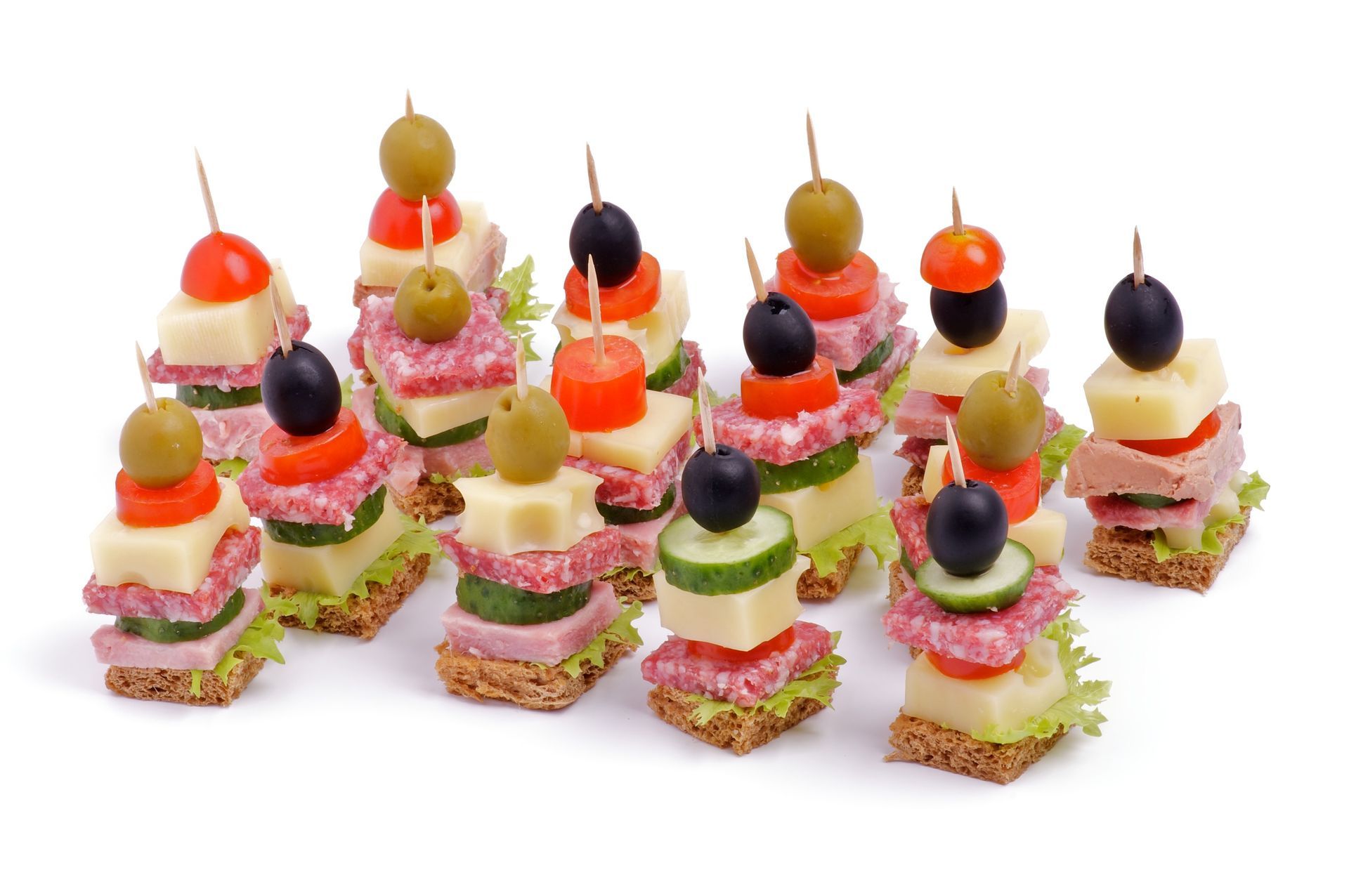 Mini layered appetizers topped with olives and colorful garnishes on a white background