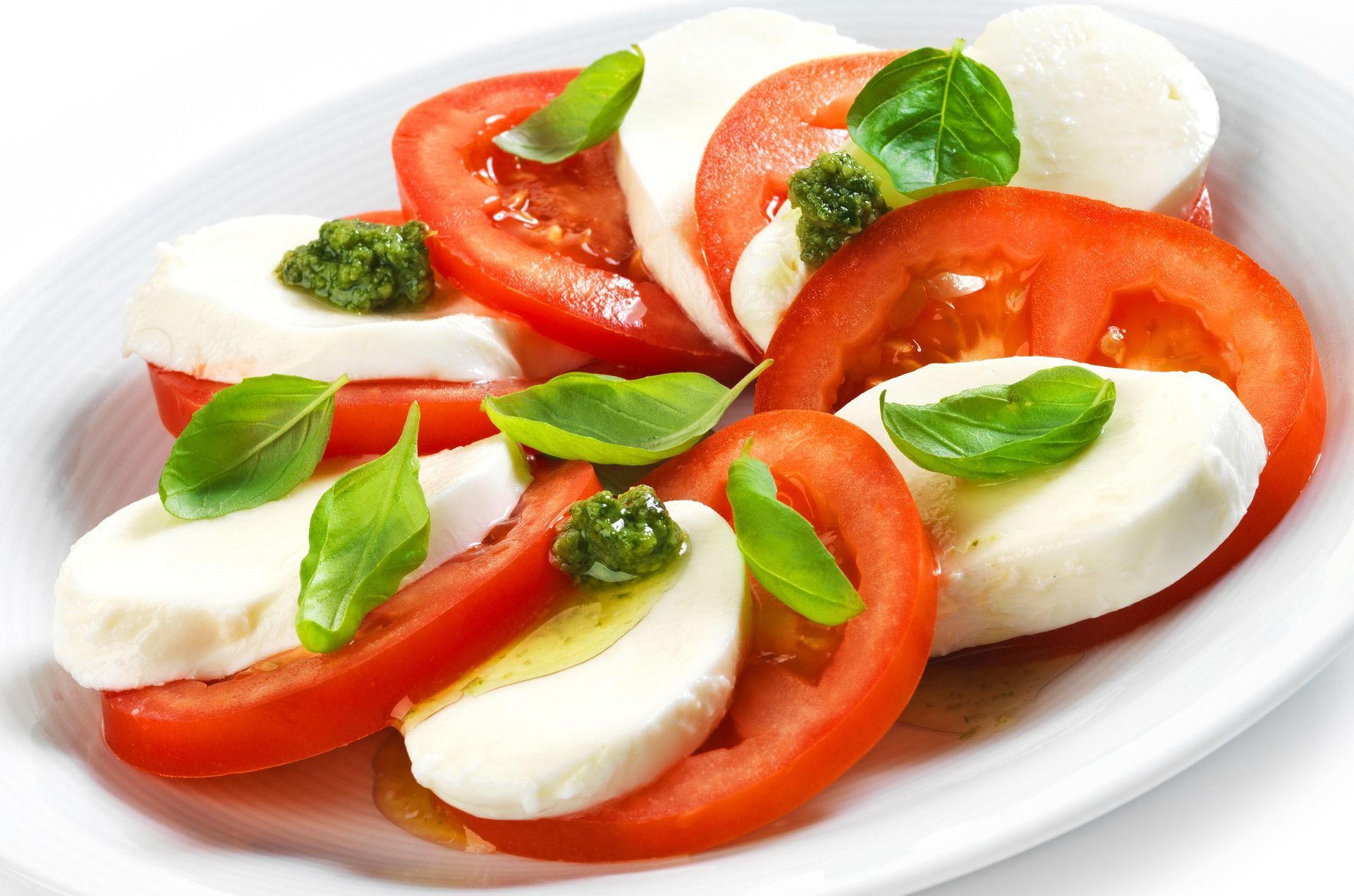 Caprese salad with sliced tomatoes, mozzarella, and basil on a white plate