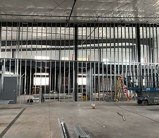 Interior view of a commercial space under construction, with metal framing for walls and upper levels. Concrete floor, unfinished.