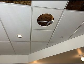 White suspended ceiling tiles with a circular hole exposing wiring; a recessed light is also visible.